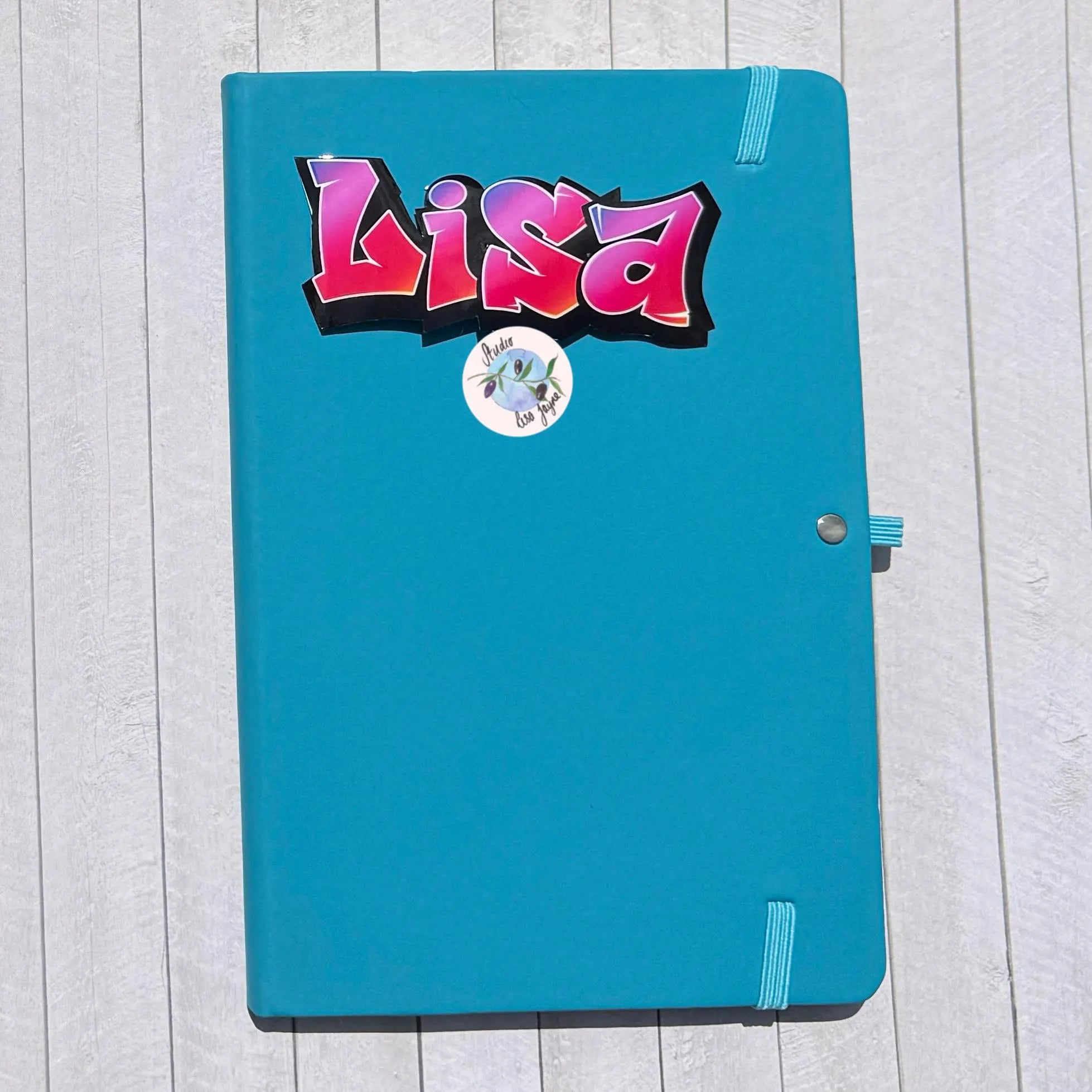 Blue notebook diary journal with a colorful 'Lisa' grafiti sticker with a purple and red gradient