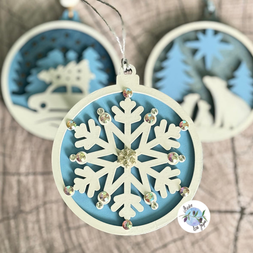 Decorative Xmas ornament with snowflake design and rhinestones in front of other designs in the same white and blue colour scheme
