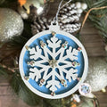 Decorative snowflake Christmas Tree ornament with rhinestones on a blurred Christmas tree background