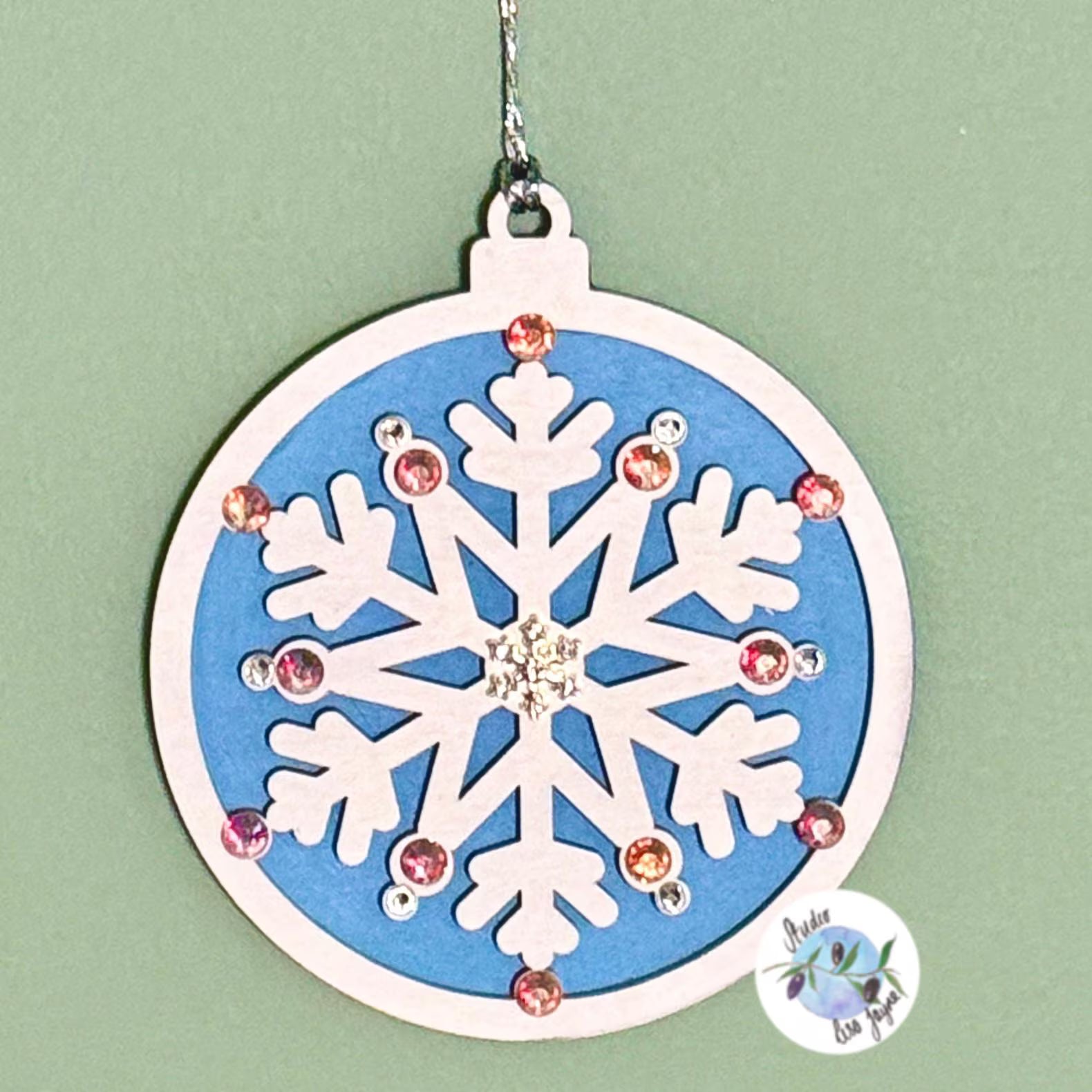 Decorative snowflake ornament with gemstones on a light green background