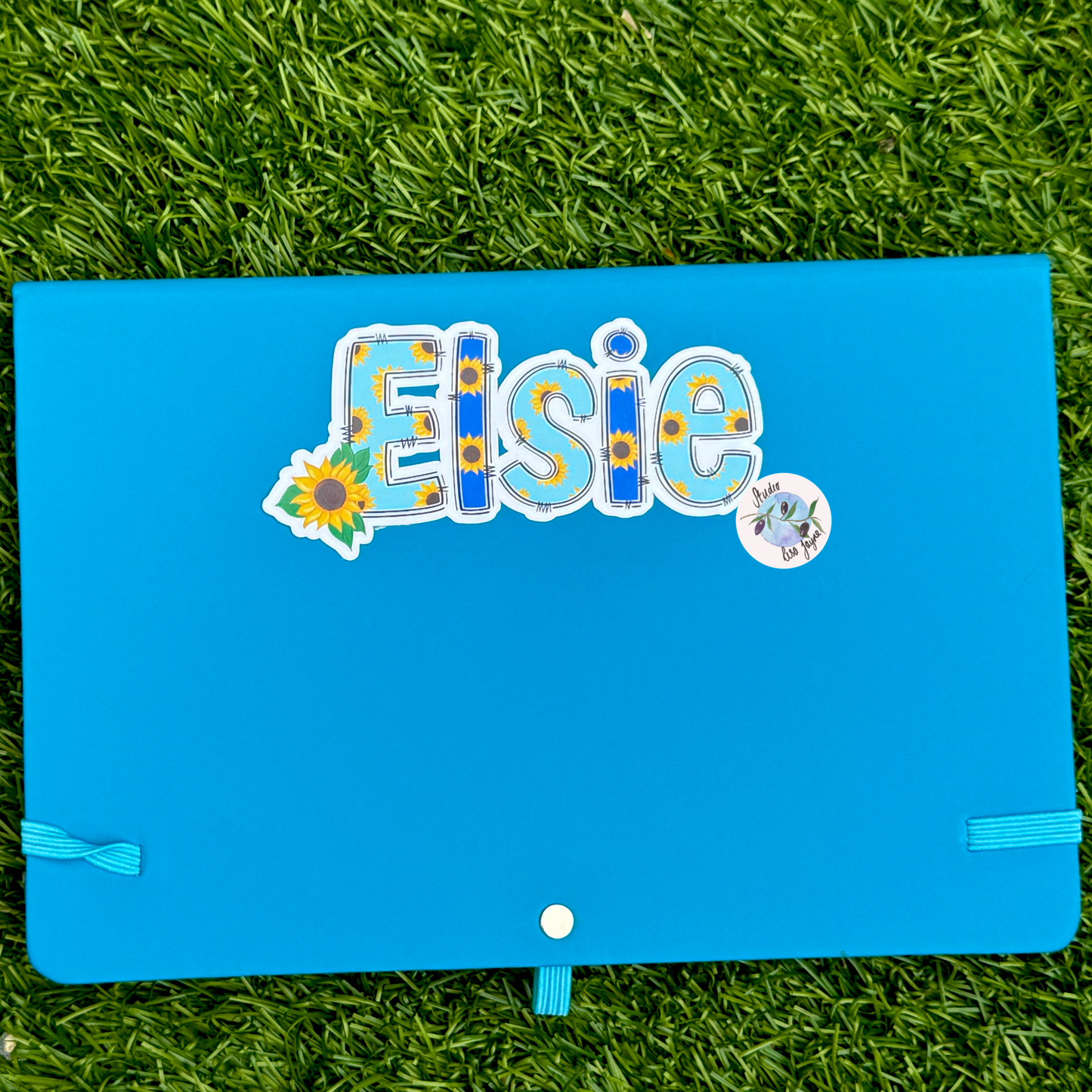 Blue notebook with decorative stickers on a grass background