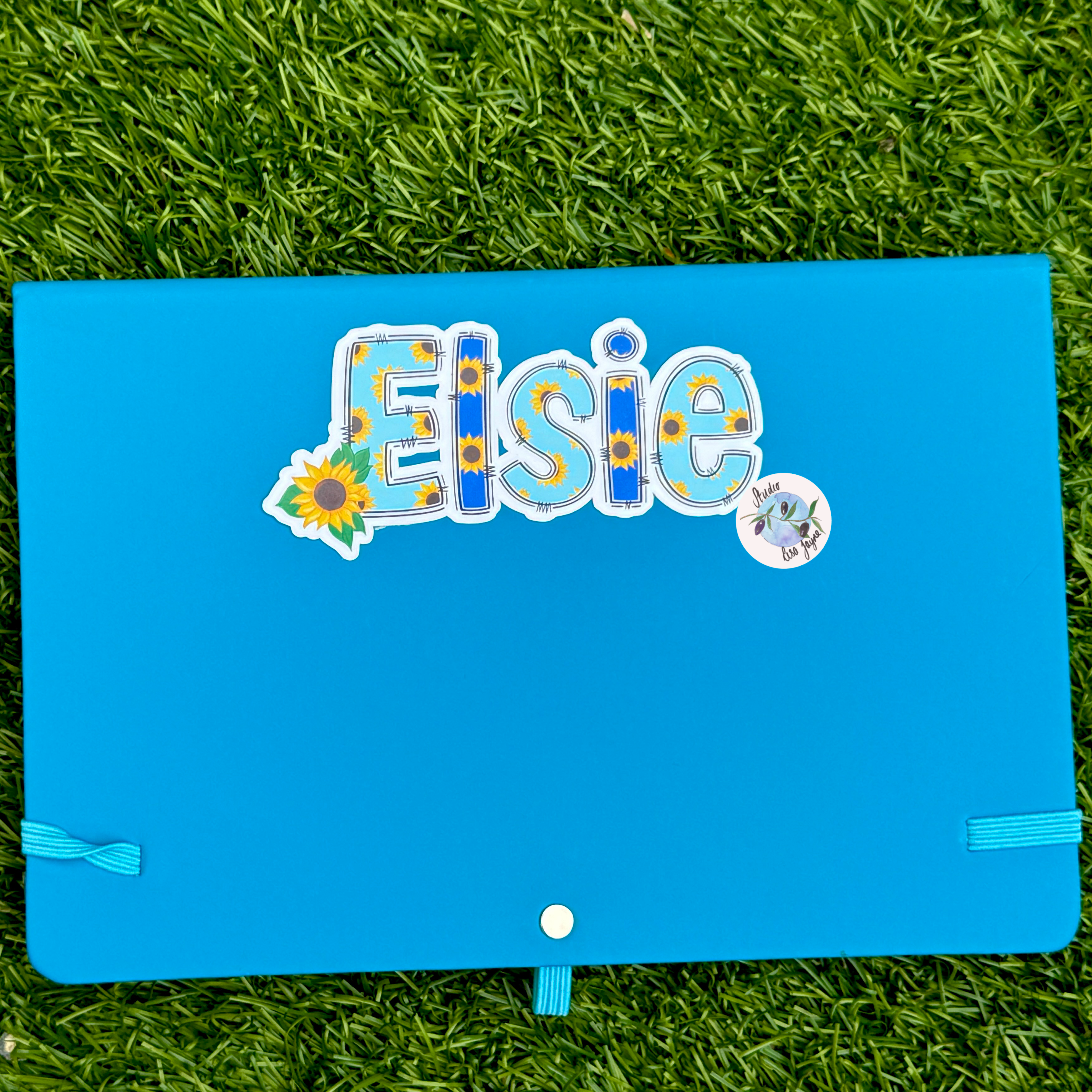 Blue notebook with decorative stickers on a grass background