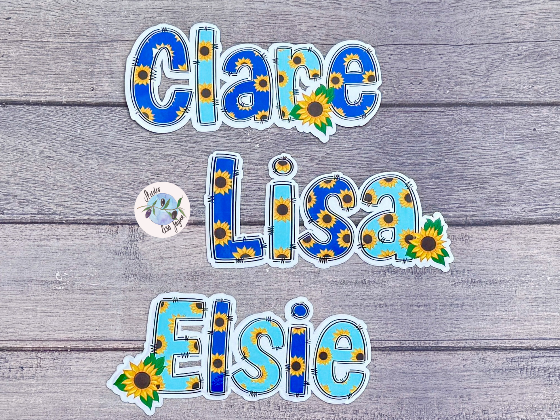 Names 'Clare', 'Lisa', and 'Elsie' with sunflower name sticker designs on a wooden background