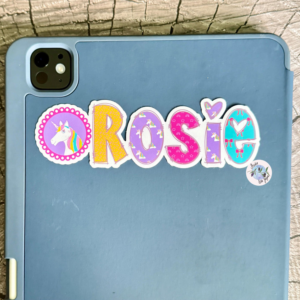 Blue ipad tablet with a colourful 'Rosie' unicorn sticker on a wooden surface