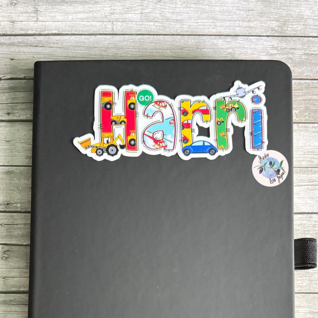 Colorful vehicle 'Harri' sticker on a black notebook with a wooden surface background