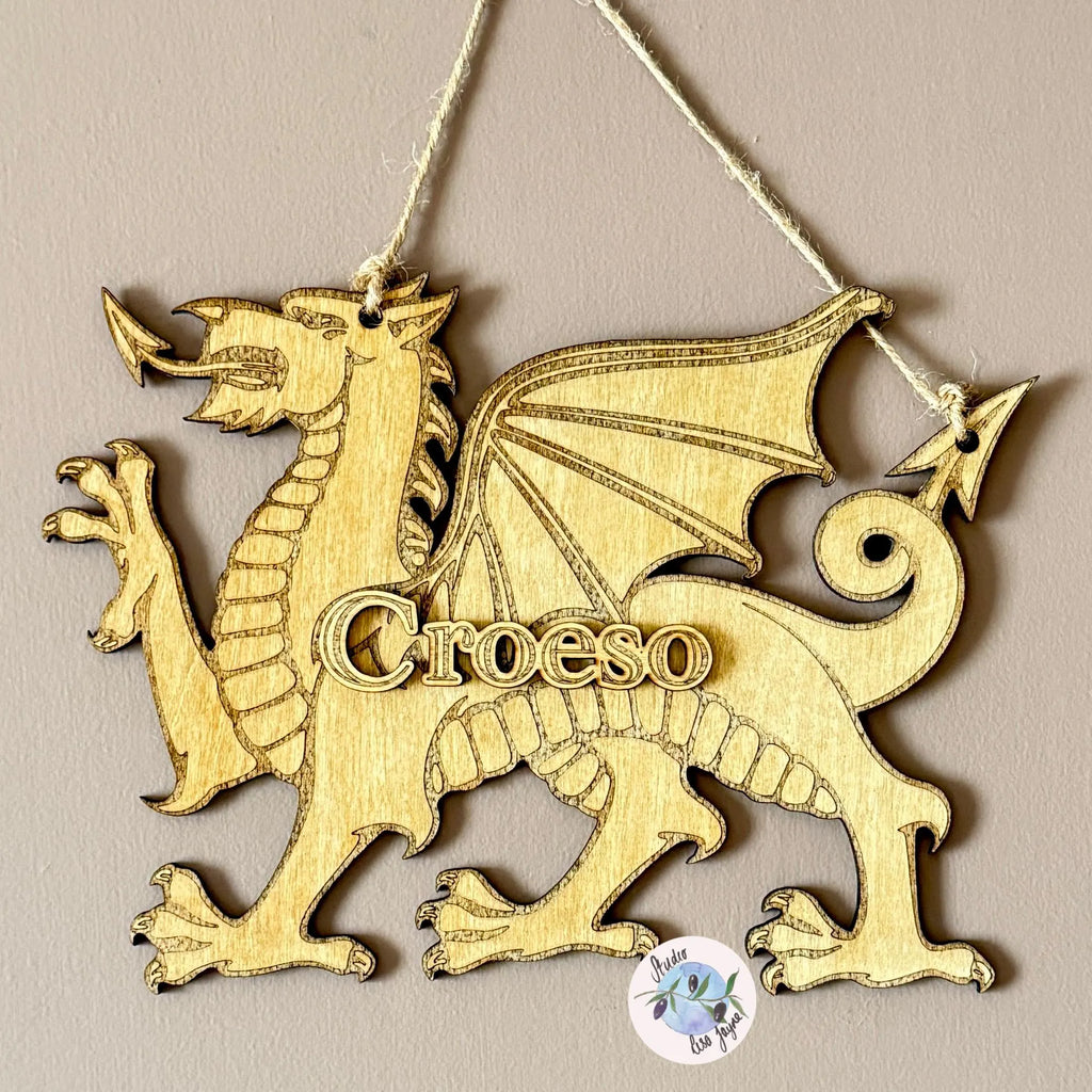 Wooden Welsh dragon decoration with 'Croeso' text hanging on a brown wall