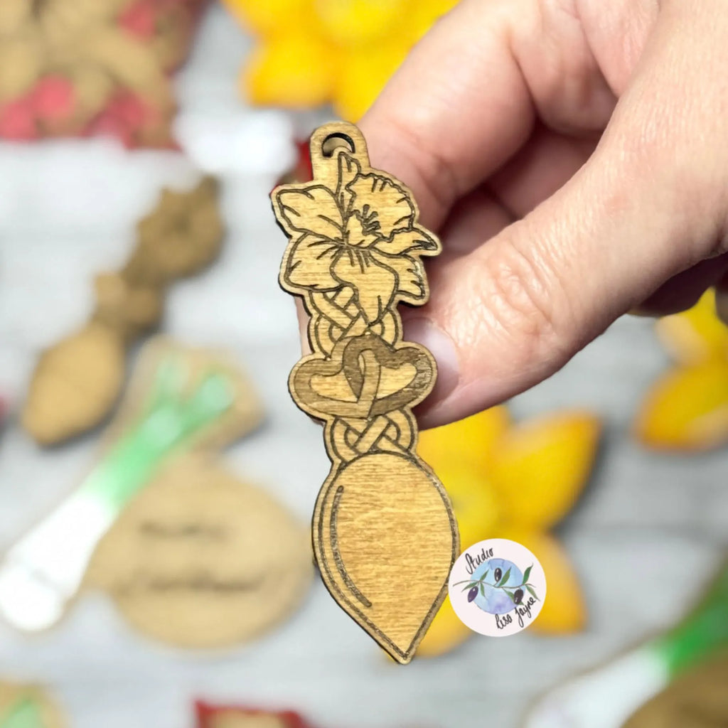 Hand holding a wooden brooch with daffodil welsh love heart design.  Ideal for St David's Day