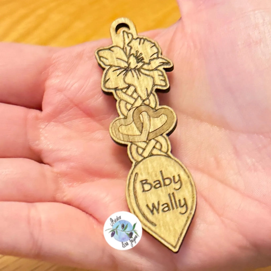Wooden brooch with daffodil welsh love spoon design and 'Baby Wally' engraving held in a hand.  Ideal for St David's Day