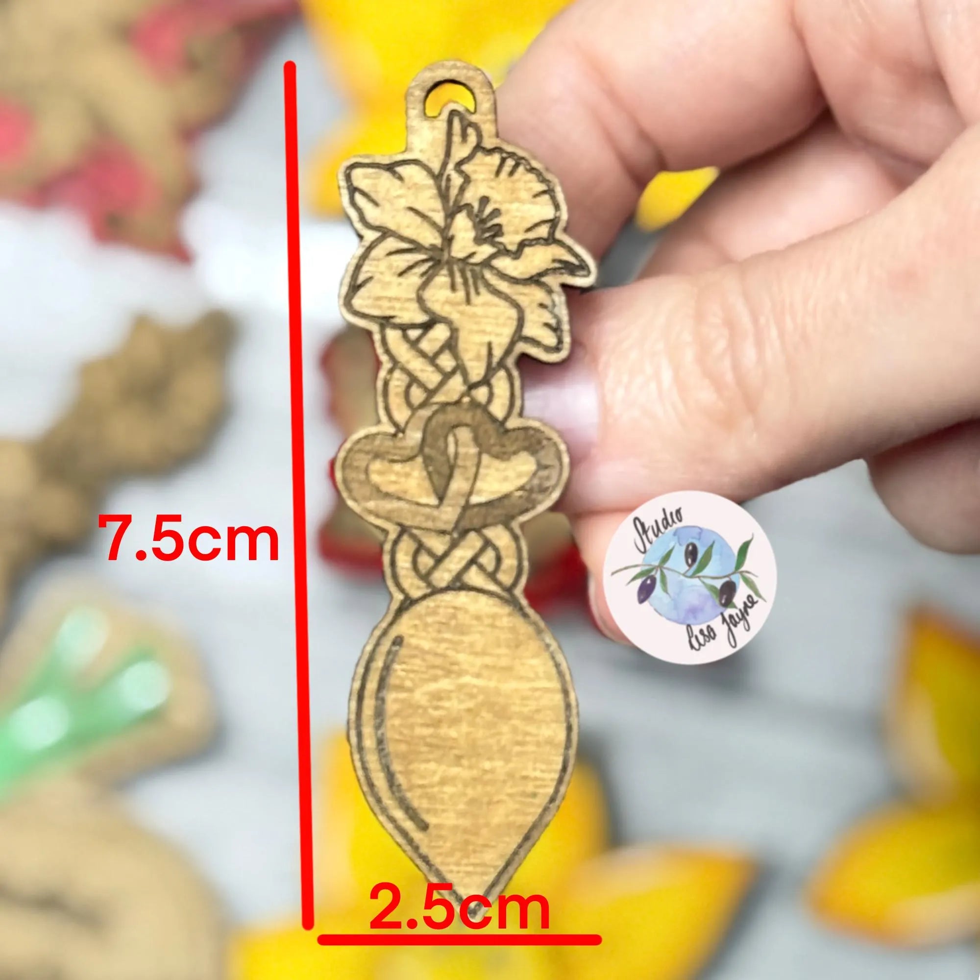 Wooden brooch of welsh love spoon with measurements and a blurred background.  Ideal for St David's Day
