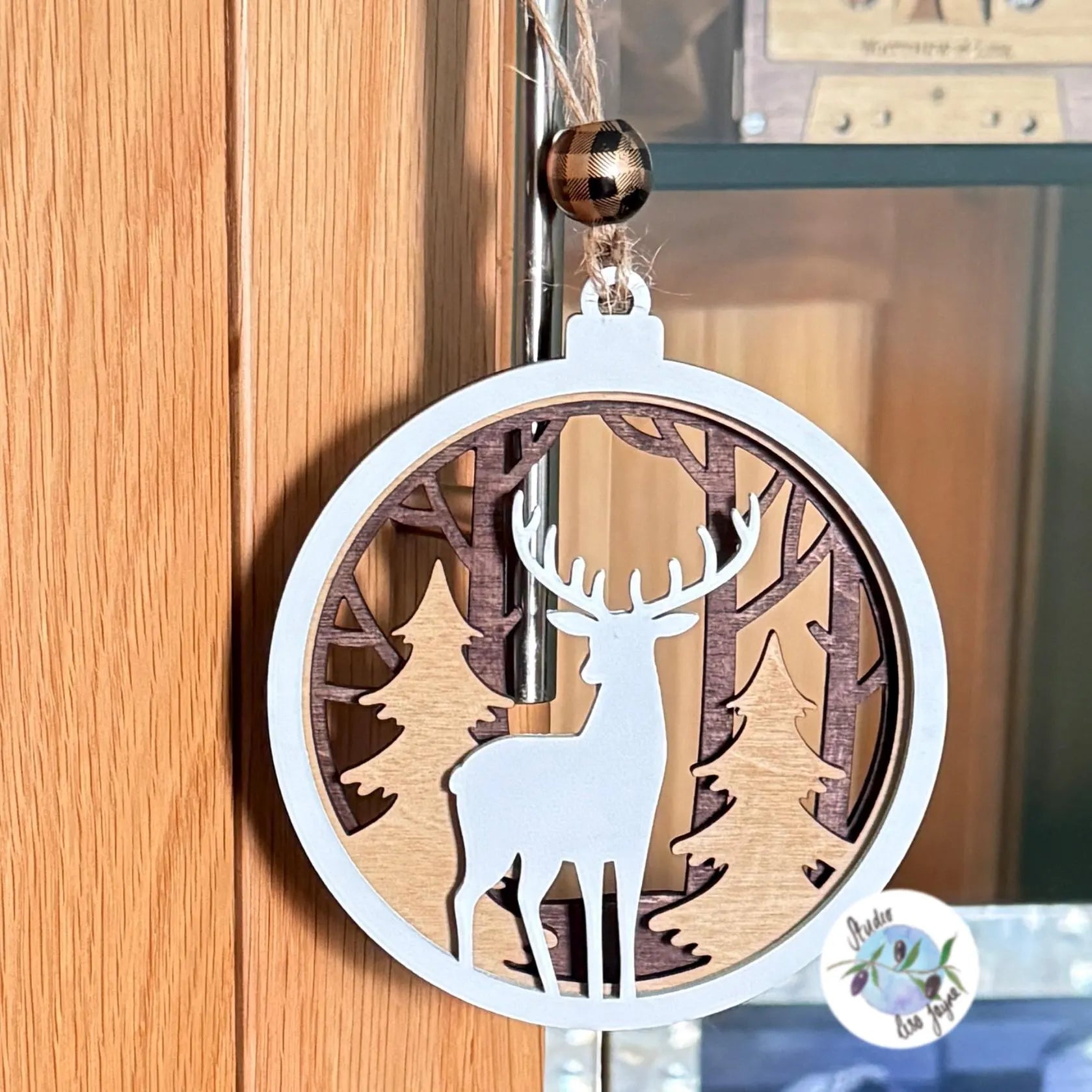 Christmas decorative ornament with reindeer and forest design hanging from a door handle