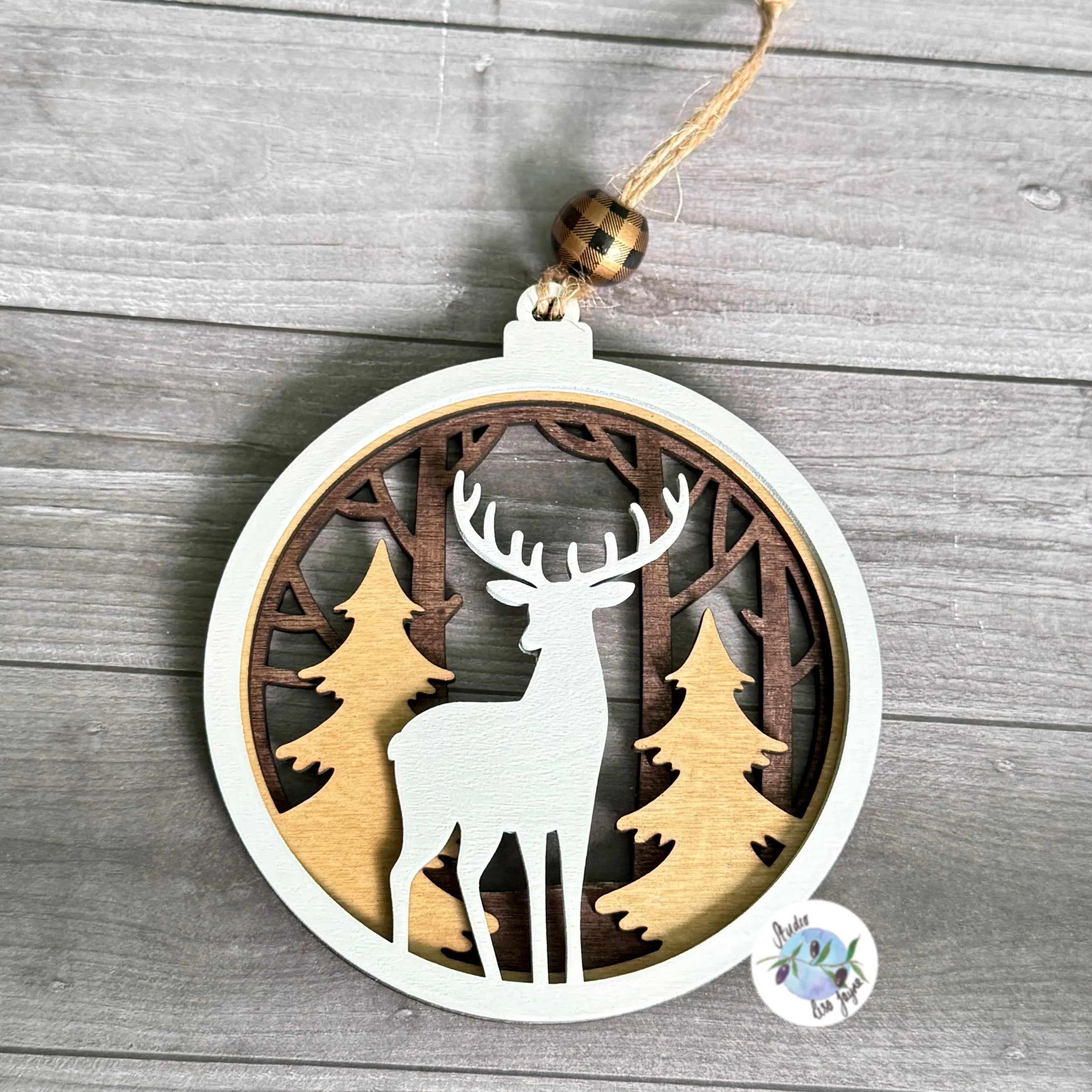 Handpainted wooden ornament with reindeer and trees design on a wooden surface.  Ideal for a modern Christmas Tree