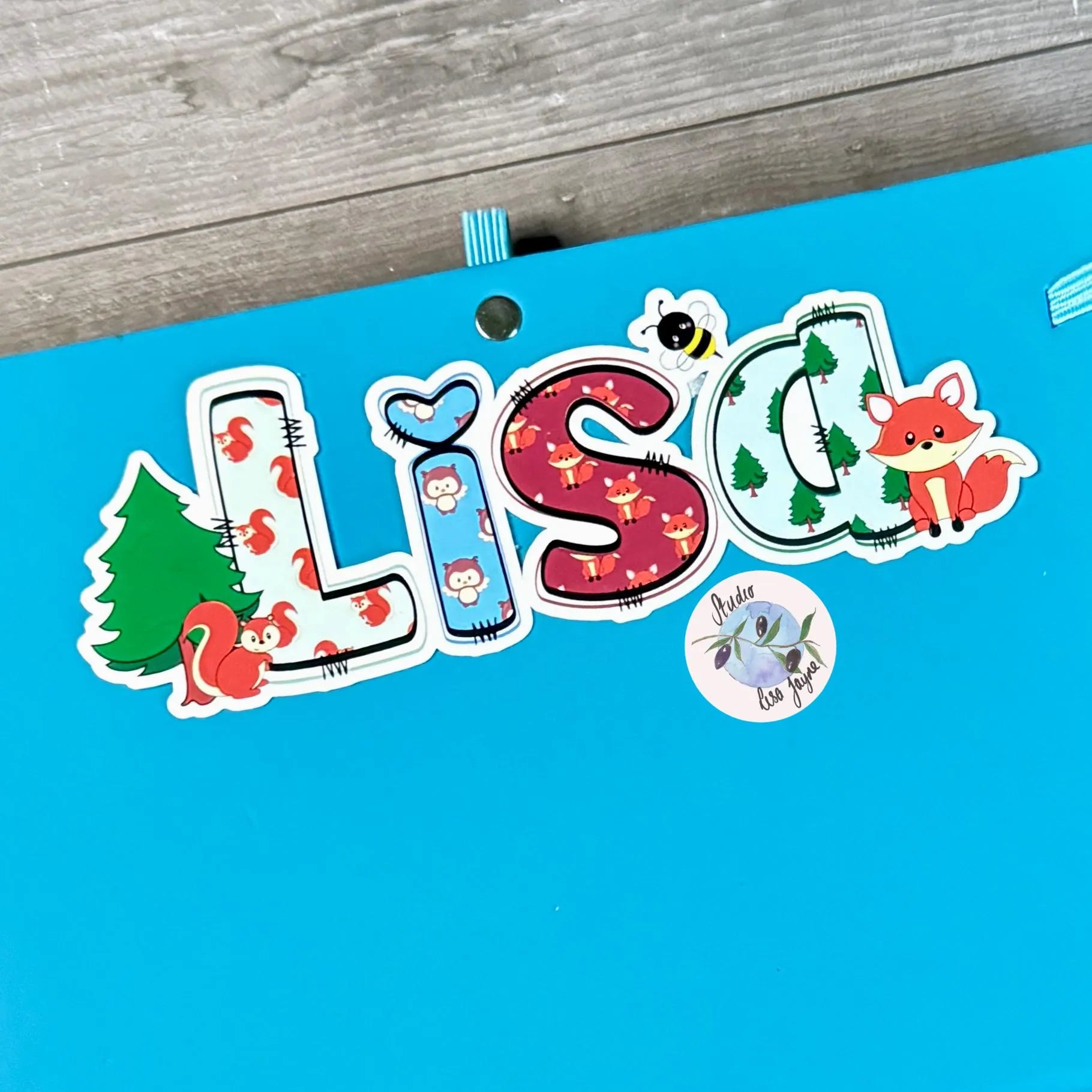 Personalised woodland animal themed name tag with 'Lisa' on a blue notebook diary