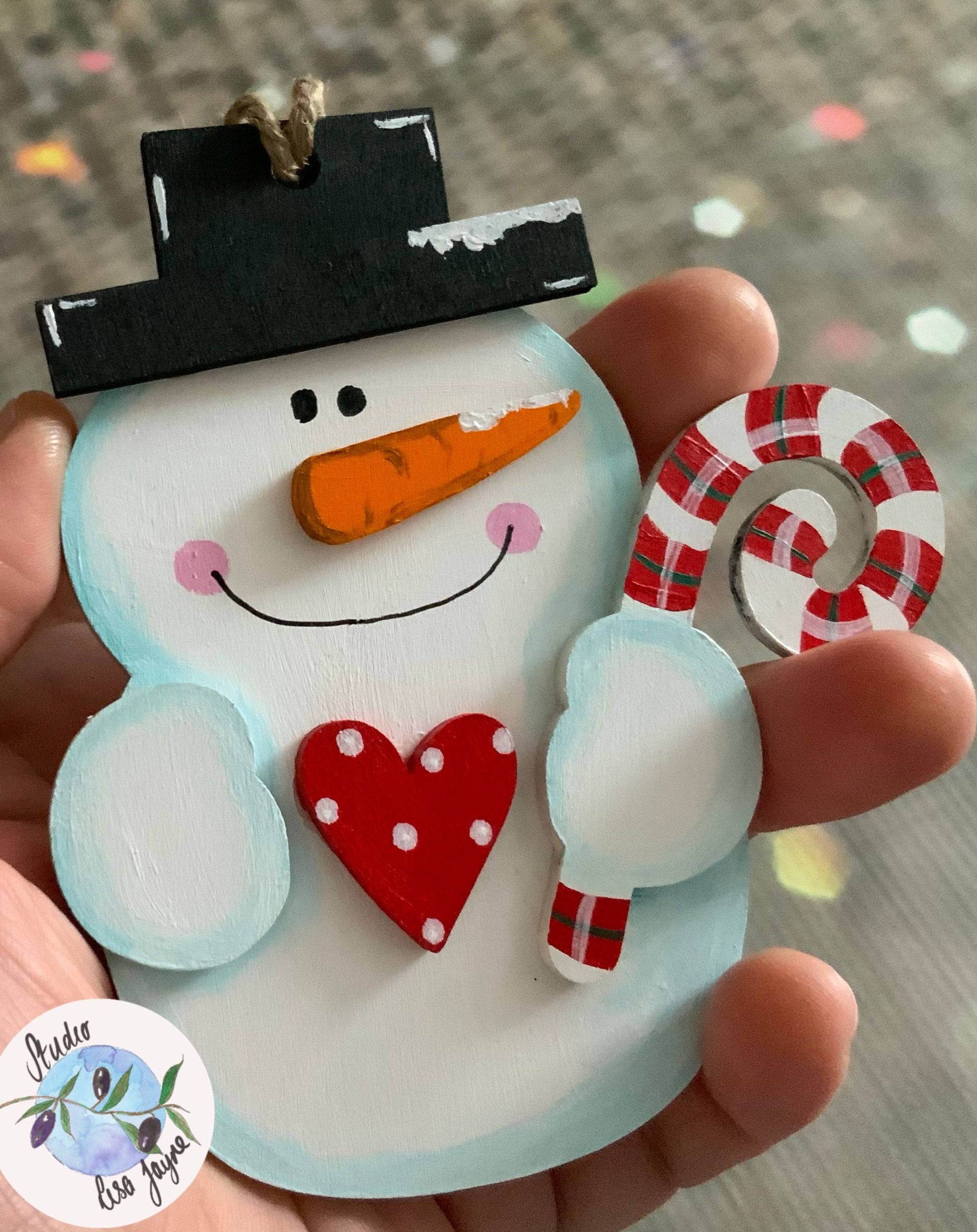 3D Hand Painted Snowman Christmas decoration holding a sugarcane with a polka dot red heart - in hand