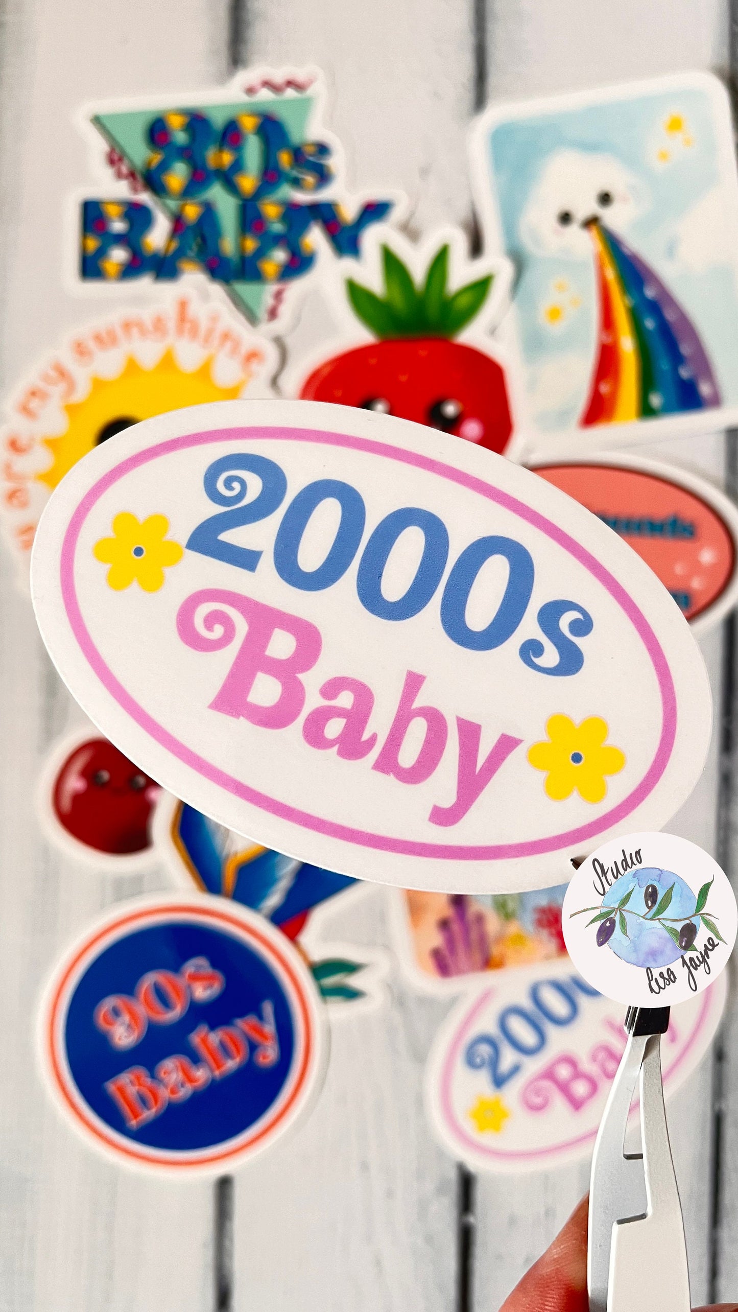 Waterproof Vinyl Sticker to celebrate people born in the 2000.  Floral 2000 Baby Sticker - In front of blurred collection of Studio Lisa Jayne sticker designs