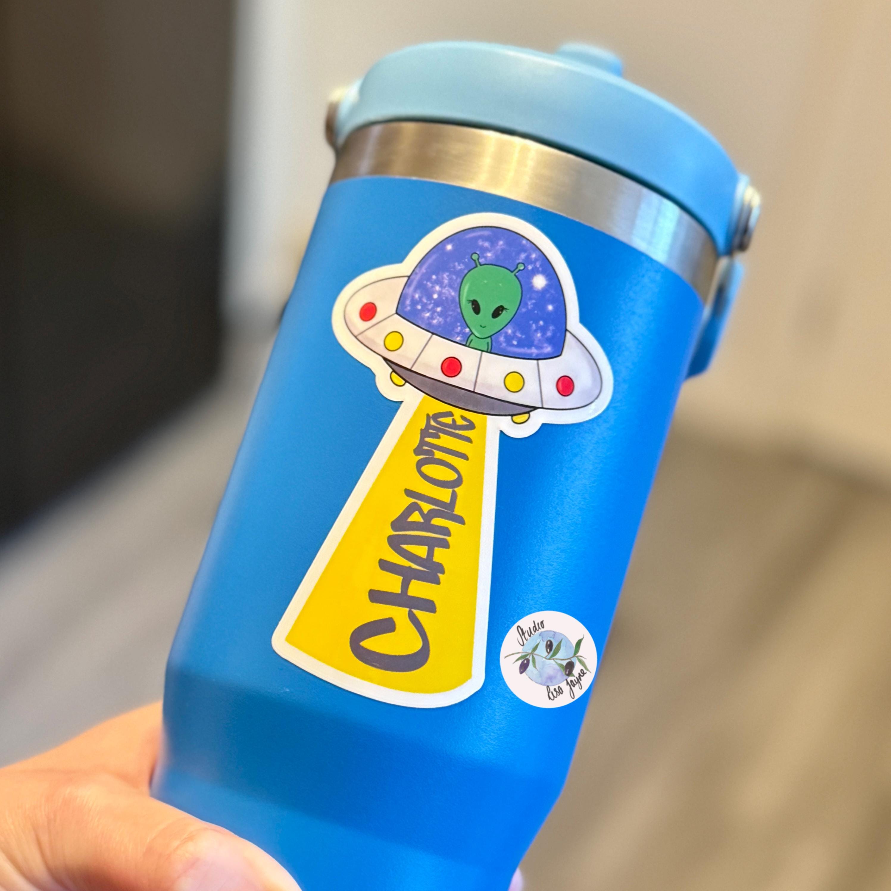 UFO Alien Name Sticker Label Kids - a hand holding a blue and silver water bottle
