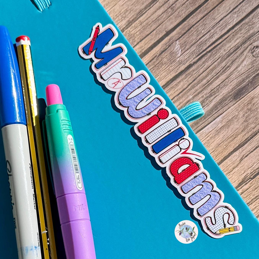 Teacher Name Sticker Label - a blue notebook with colorful markers on it