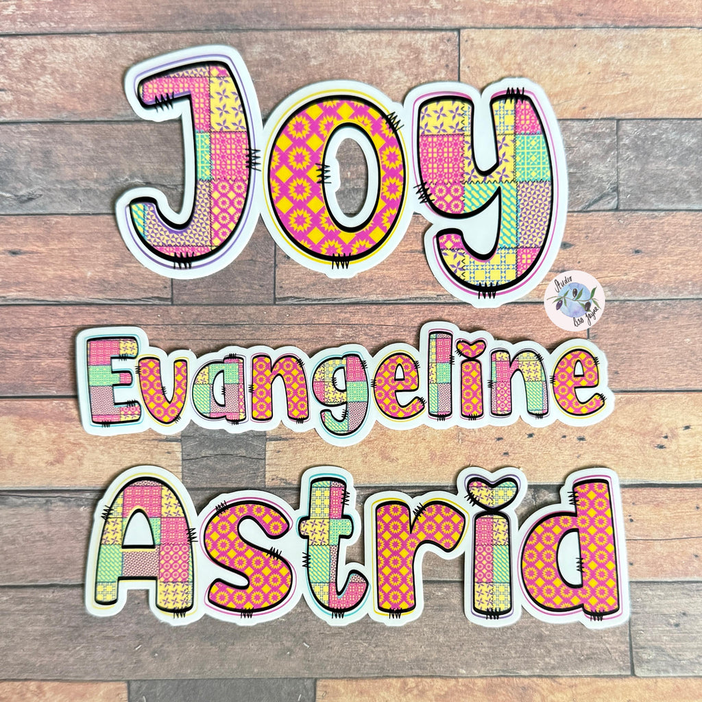 Patchwork Style Name Sticker Label - a group of colorful letters on a wood surface