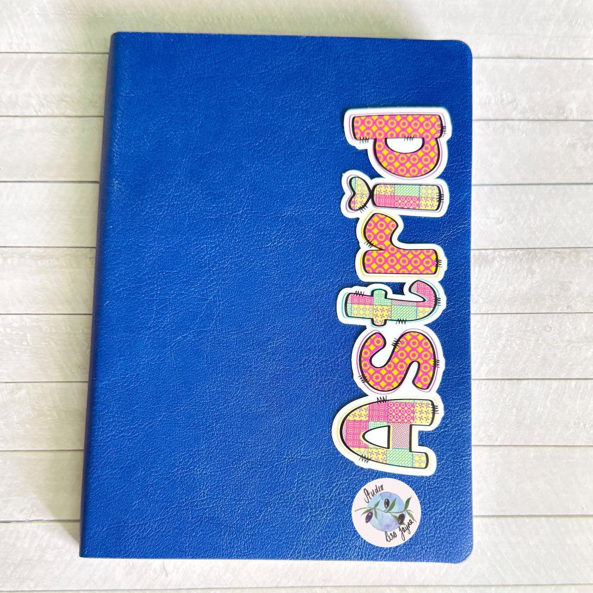 Patchwork Style Name Sticker Label - a blue notebook with a sticker on it