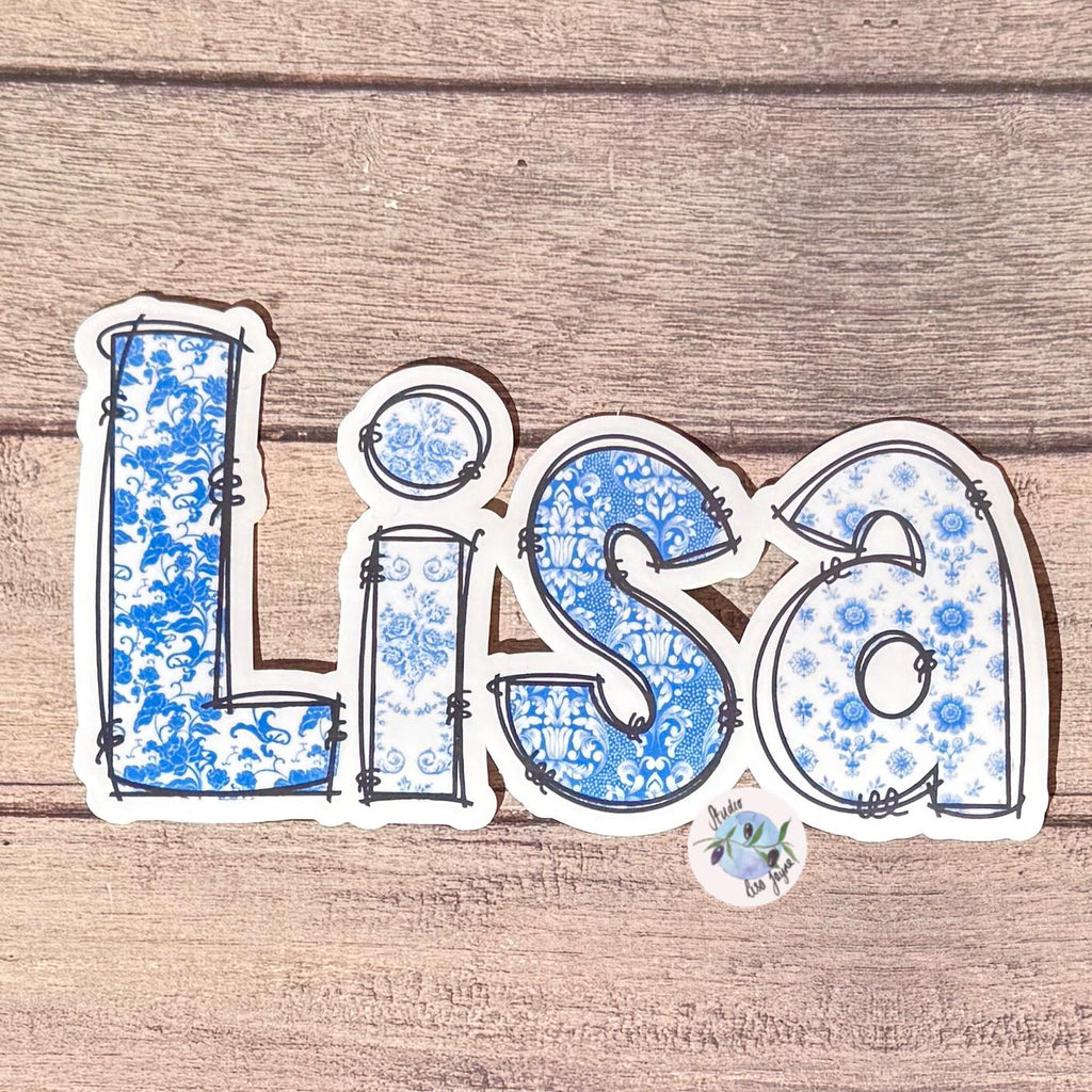 Floral Blue and White Name Sticker Label Kids - a blue and white sticker with blue letters on a wood surface