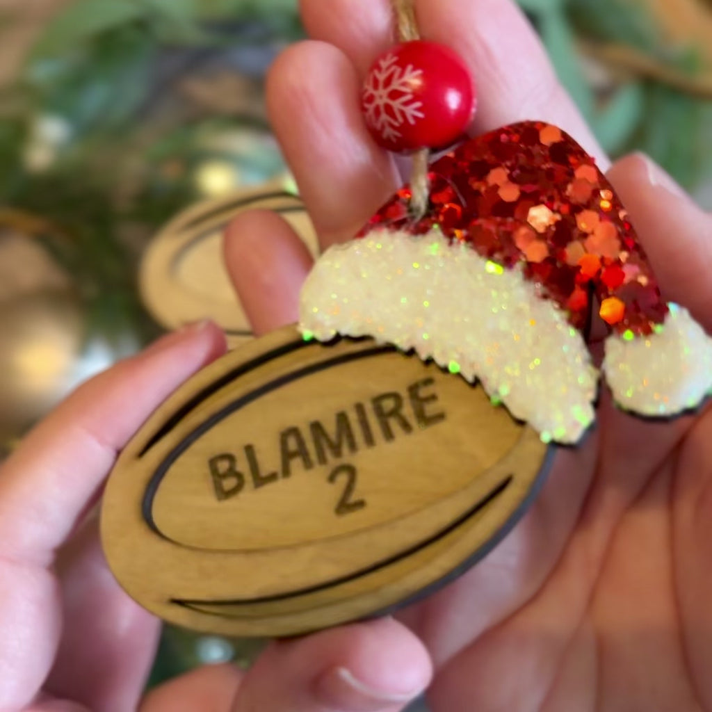 Personalised Christmas rugby ball tree decoration with red and white glittered Santa hat