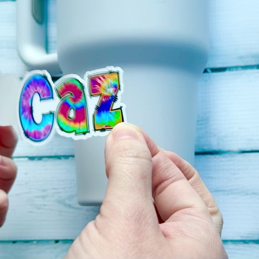 Waterproof Vinyl Tie Dye Name Sticker being applied to drink bottle